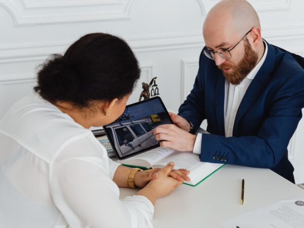 Avocat et cliente examinant ensemble le rapport d’expertise d’un véhicule sur tablette