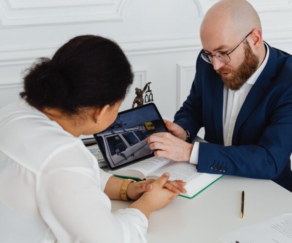 Avocat et cliente examinant ensemble le rapport d’expertise d’un véhicule sur tablette