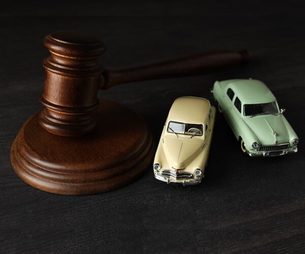Marteau de juge placé à côté de deux voitures miniatures, symbolisant l’expertise judiciaire en vice caché automobile