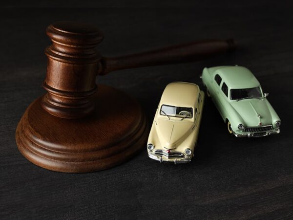 Marteau de juge placé à côté de deux voitures miniatures, symbolisant l’expertise judiciaire en vice caché automobile